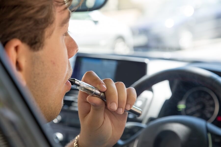 Teen smoking e cigarette in car while driving