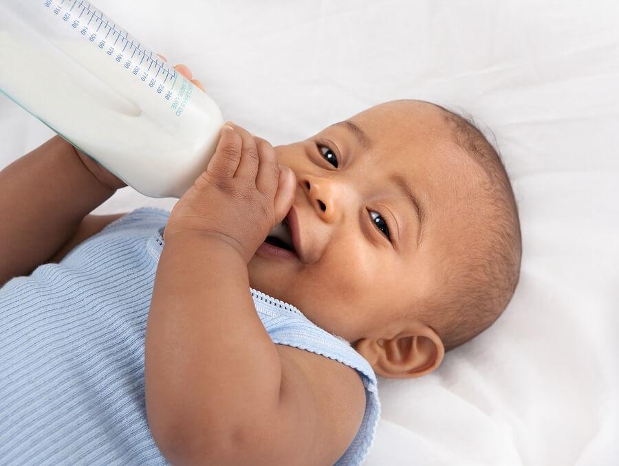 Baby boy laying on back drinking bottle