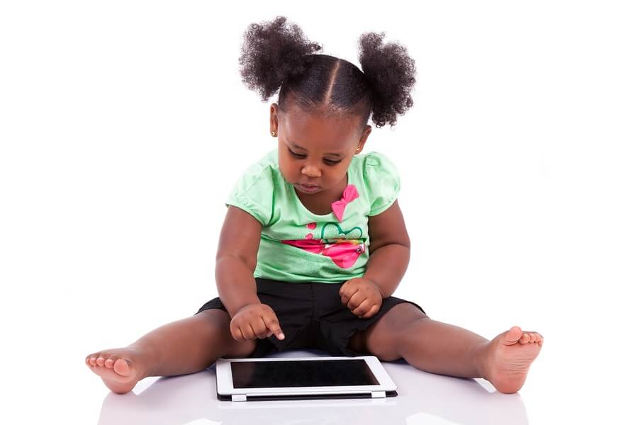 Little girl with pigtails using tablet against white background