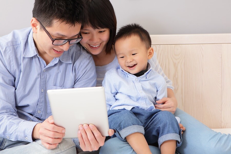 Happy family sitting on couch using tablet