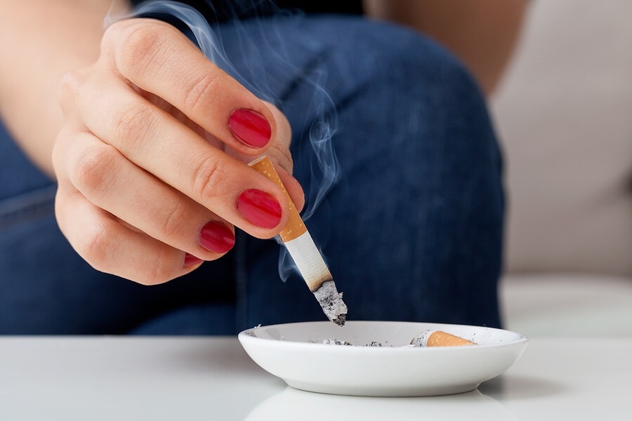 Hand holding cigarette over ashtray