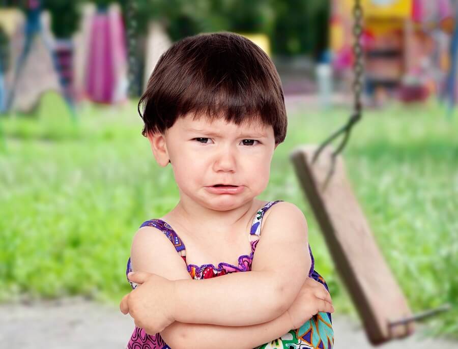 Crying girl with broken swing in background