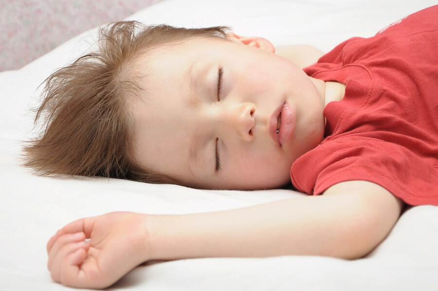 Little boy sleeping on back in bed