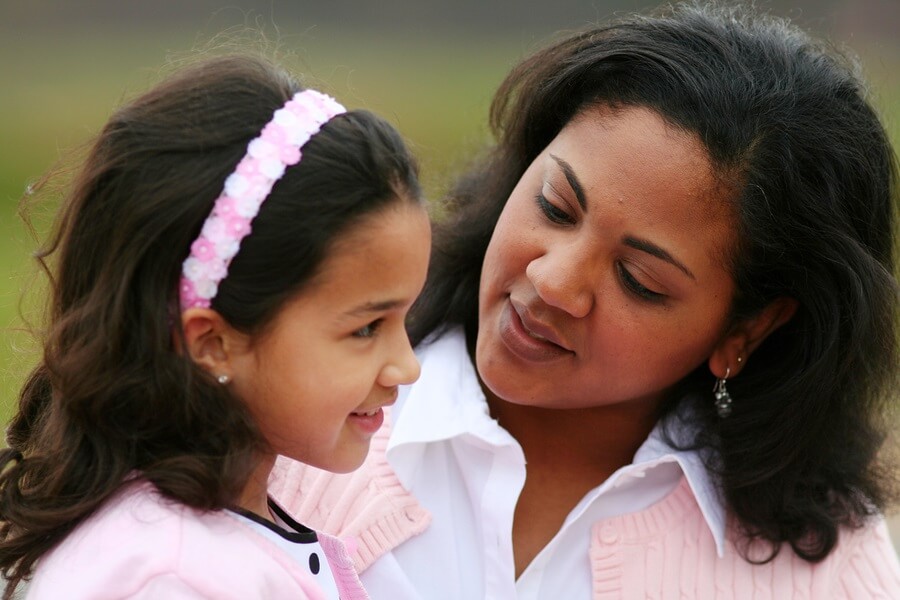 Concerned mother talking to smiling daughter