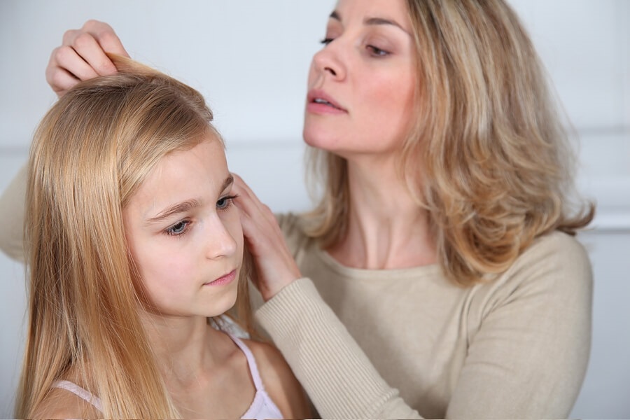 Mom checking young daughter for ticks