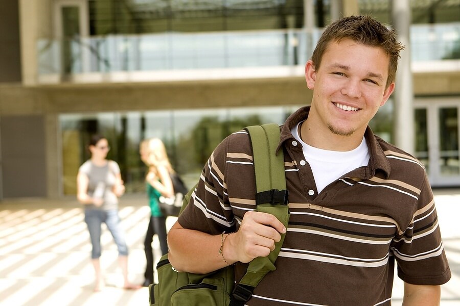 Male student standing in front of school with backpack