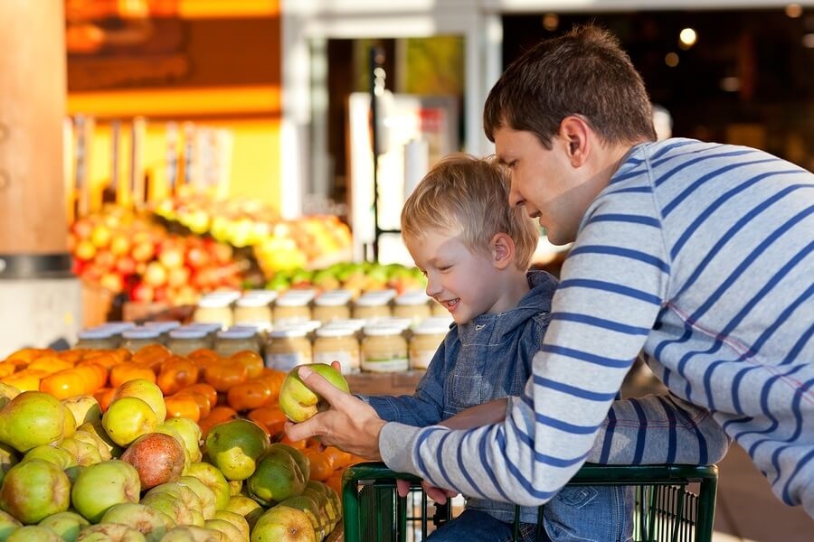 Father and son at farmers market picking out fruit