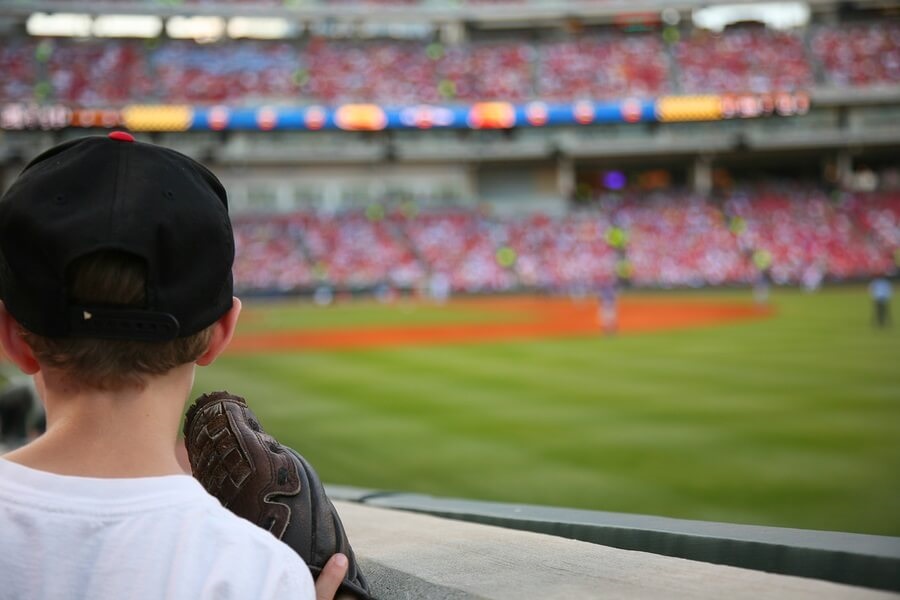 Little boy holding glove at baseball game