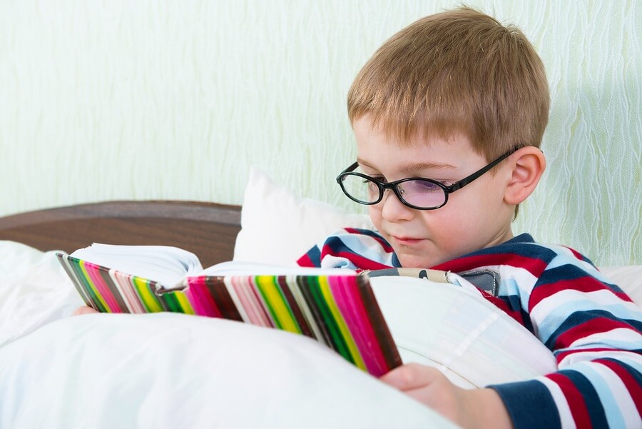 Little boy relaxing in bed reading.