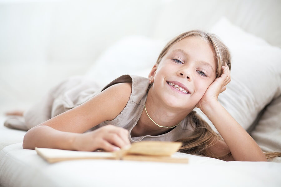 Young girl laying on sofa reading book