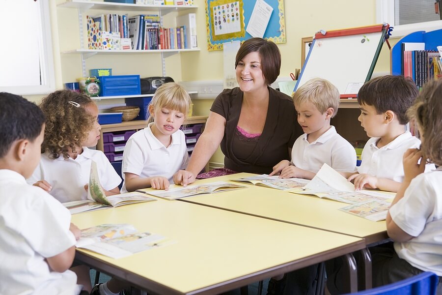 Students and teacher practicing reading around table