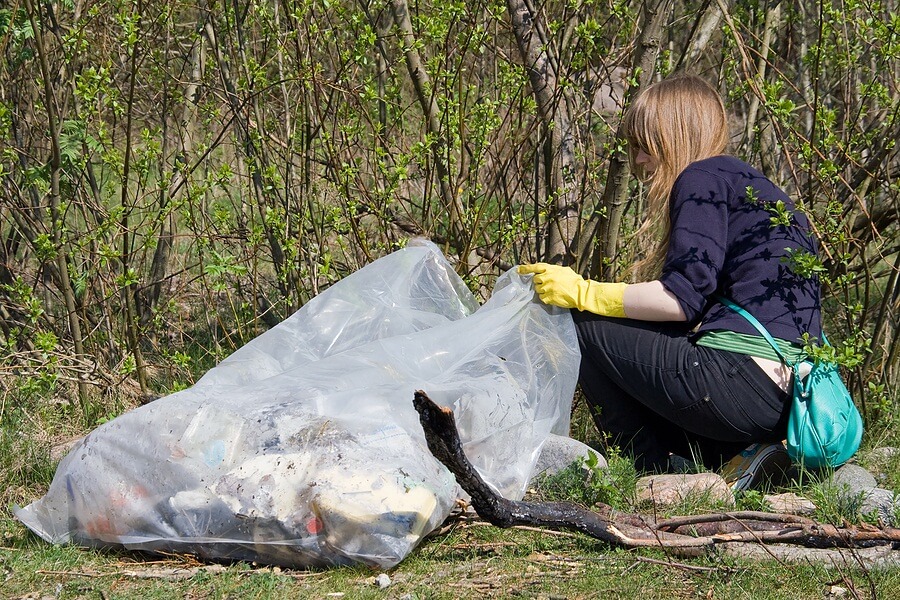 Girl picking up trash along road