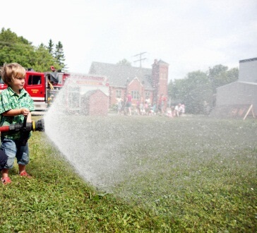 Little boy having fun spraying fire house