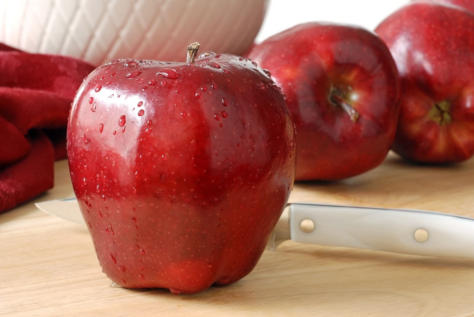 Close up of apple on cutting board with knife.