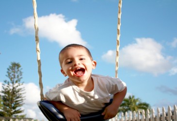 Happy boy on swingset in summer time