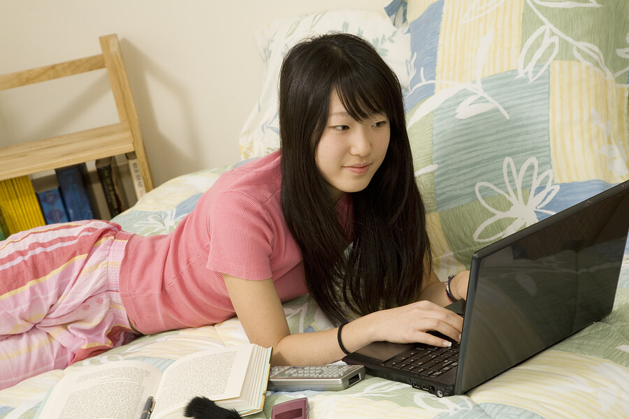 AsianAmericaninbedroomwithlaptopcomputer