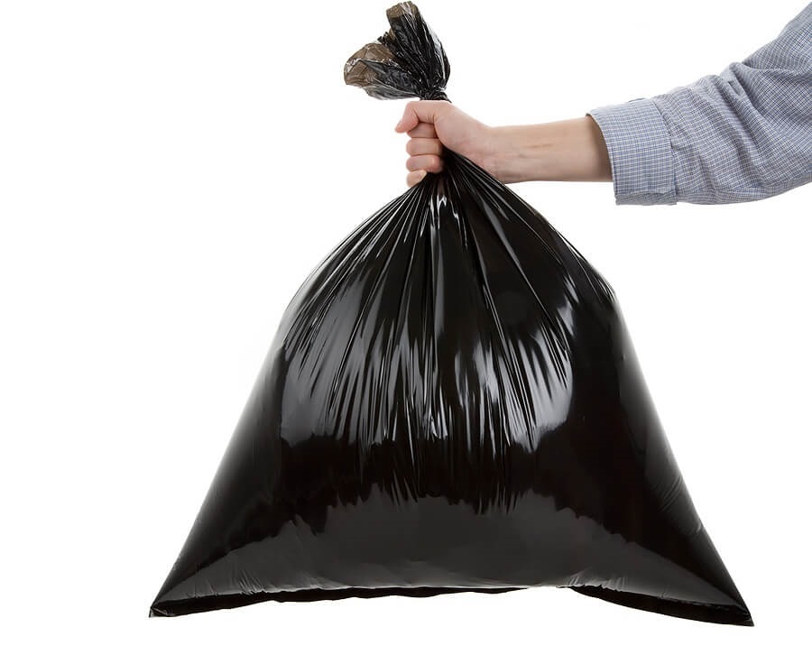 Hand hold trash bag against white backdrop